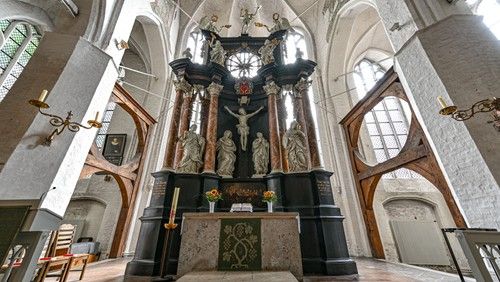 Innenansicht einer Kirche mit einem reich verzierten Altar und hohen Gewölbedecken.