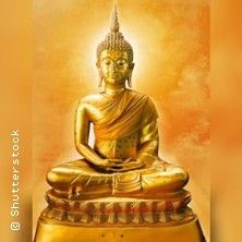 Goldene Buddha-Statue vor einem orangefarbenen Hintergrund.