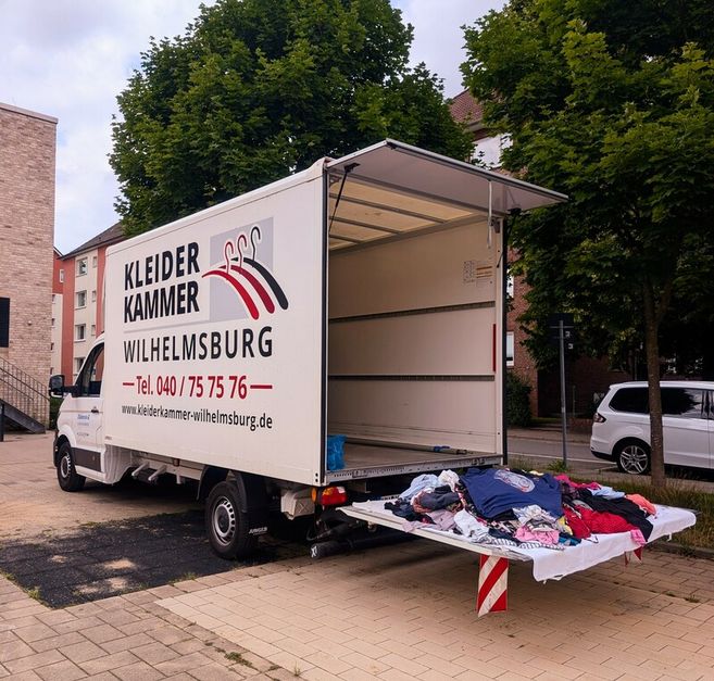 Ein geöffneter Lieferwagen der Kleiderkammer Wilhelmsburg mit Kleidung auf der Ladefläche.