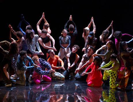 Excerpt from Marco da Silva Ferreira’s “A Folia.” A group of dancers stands in a semicircle wearing colorful costumes.