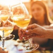 Menschen stoßen mit Weingläsern an, im Hintergrund unscharf eine Frau.