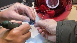 Zwei Personen reparieren ein elektronisches Gerät mit einem Lötkolben.