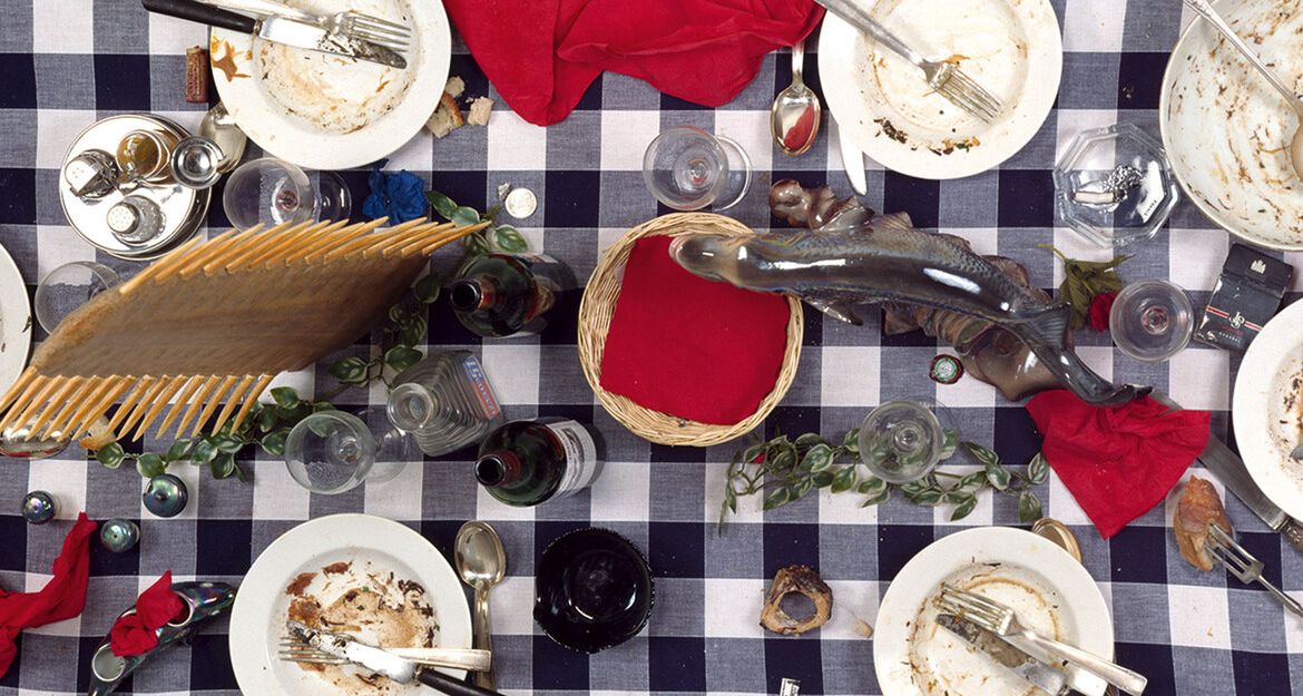 Kunstinstallation von Daniel Spoerri mit benutztem Geschirr auf kariertem Tischtuch.