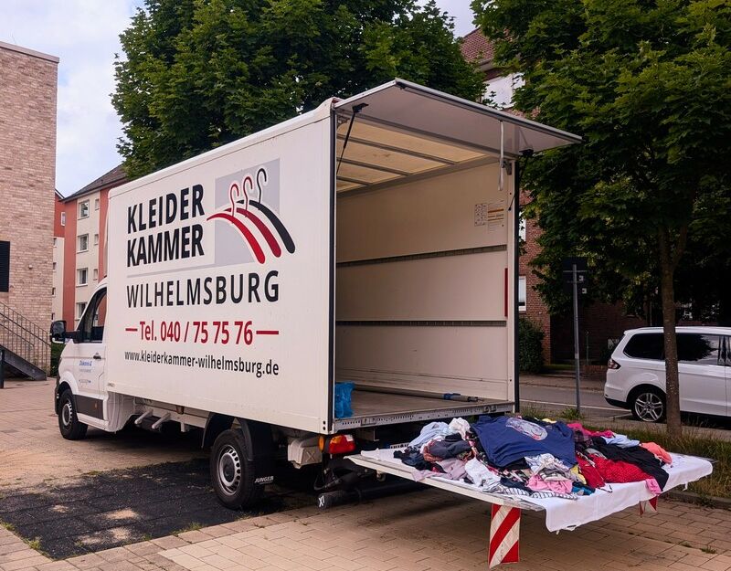 Ein geöffneter Lieferwagen der Kleiderkammer Wilhelmsburg mit Kleidung auf der Ladefläche.