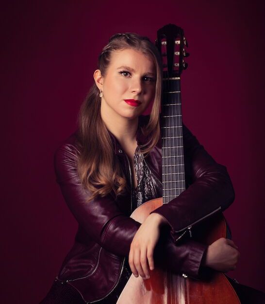 Frau mit Gitarre vor rotem Hintergrund