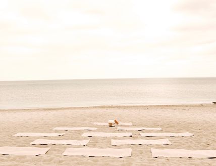 Yoga-Matten auf einem sandigen Strand mit Blick auf das Meer.