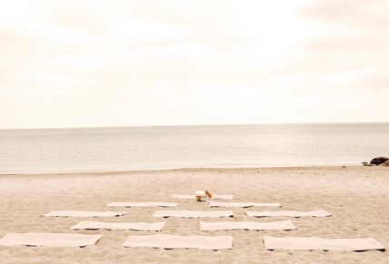 Yoga-Matten auf einem sandigen Strand mit Blick auf das Meer.