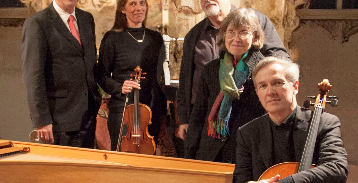 Fünf Musiker posieren mit Instrumenten vor einem Altar.