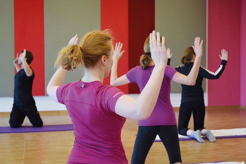 Menschen in einem Fitnesskurs machen Rückenübungen auf Matten.