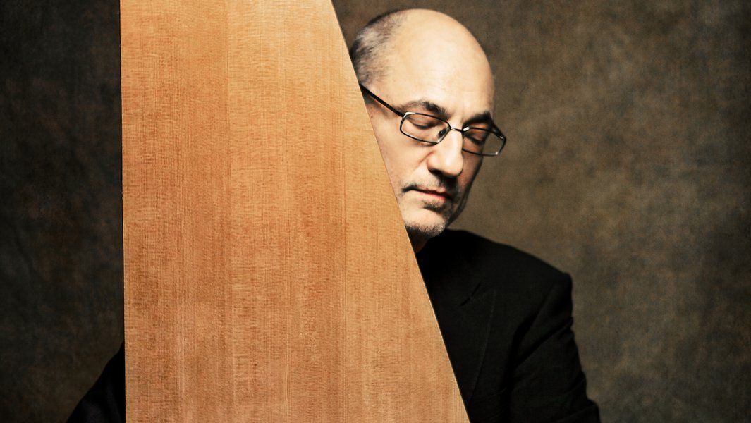 Ein Mann mit Brille hinter einem Holzinstrument, die Augen geschlossen.