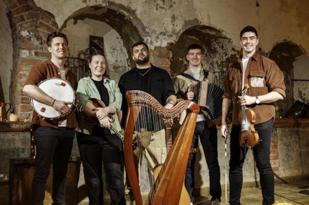 Fünf Musiker mit traditionellen irischen Instrumenten in einem rustikalen Raum.