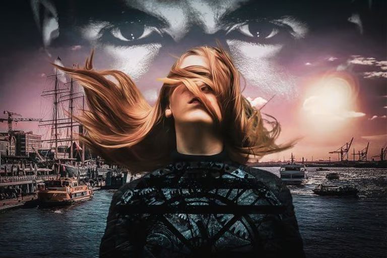 Eine Frau mit wehenden Haaren steht vor einem Hafen bei Sonnenuntergang, über ihr ein großes, geheimnisvolles Augenpaar am Himmel. Die Stimmung ist düster und emotional.