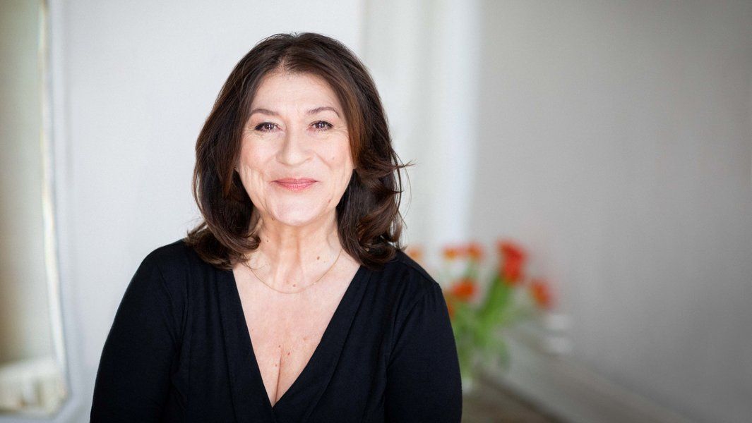 Porträt einer lächelnden Frau mit dunklem Haar in einem schwarzen Oberteil.