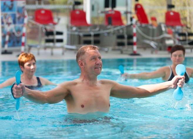 Menschen machen Aqua-Fitness-Übungen in einem Schwimmbad.