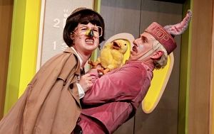 Zwei Personen in Kostümen mit einem gelben Plüschküken in einem humorvollen Szenario.