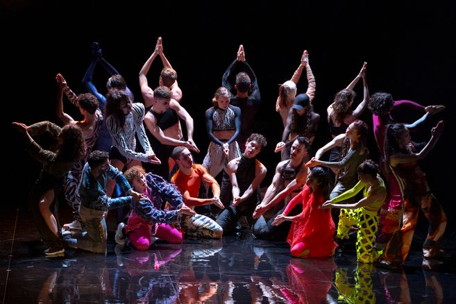 Excerpt from Marco da Silva Ferreira’s “A Folia.” A group of dancers stands in a semicircle wearing colorful costumes.