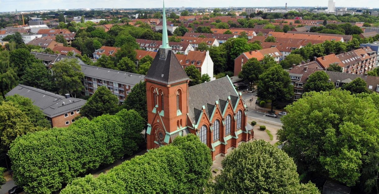 Luftaufnahme einer Kirche in einer Wohngegend mit vielen Bäumen.