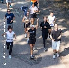 Eine Gruppe von Menschen joggt auf einem Weg im Freien.