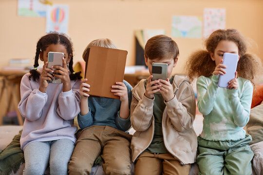 Group of young children holding smartphones and hiding faces, gen Alpha, © Seventyfours/stock.adobe.com