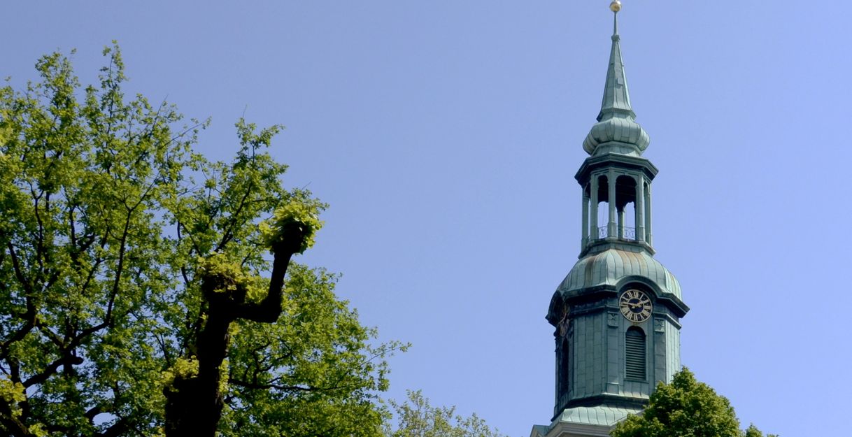 Turm der Dreieinigkeitskirche St. Georg mit Bäumen im Vordergrund.