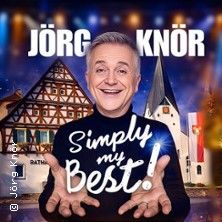 Jörg Knör vor einem Fachwerkhaus und einer Kirche mit dem Schriftzug 'Simply my Best!'
