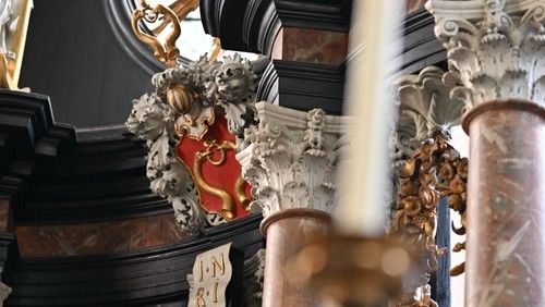 Nahaufnahme eines verzierten Kirchenaltars mit Wappen und Säulen.