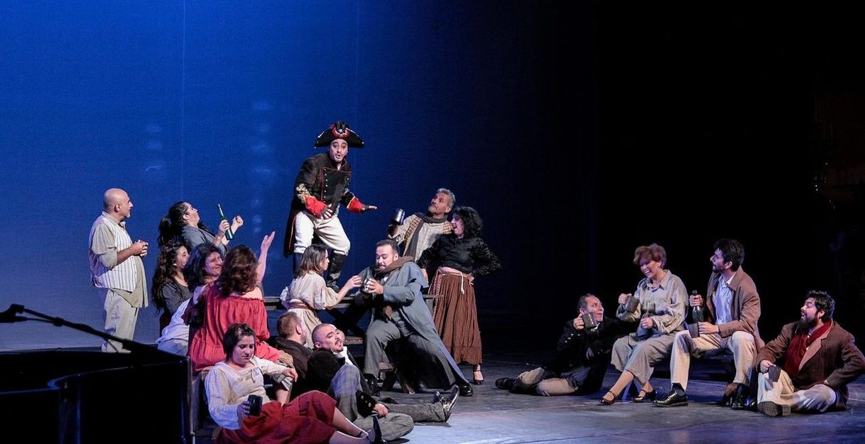 Theaterszene mit Schauspielern in historischen Kostümen auf der Bühne.