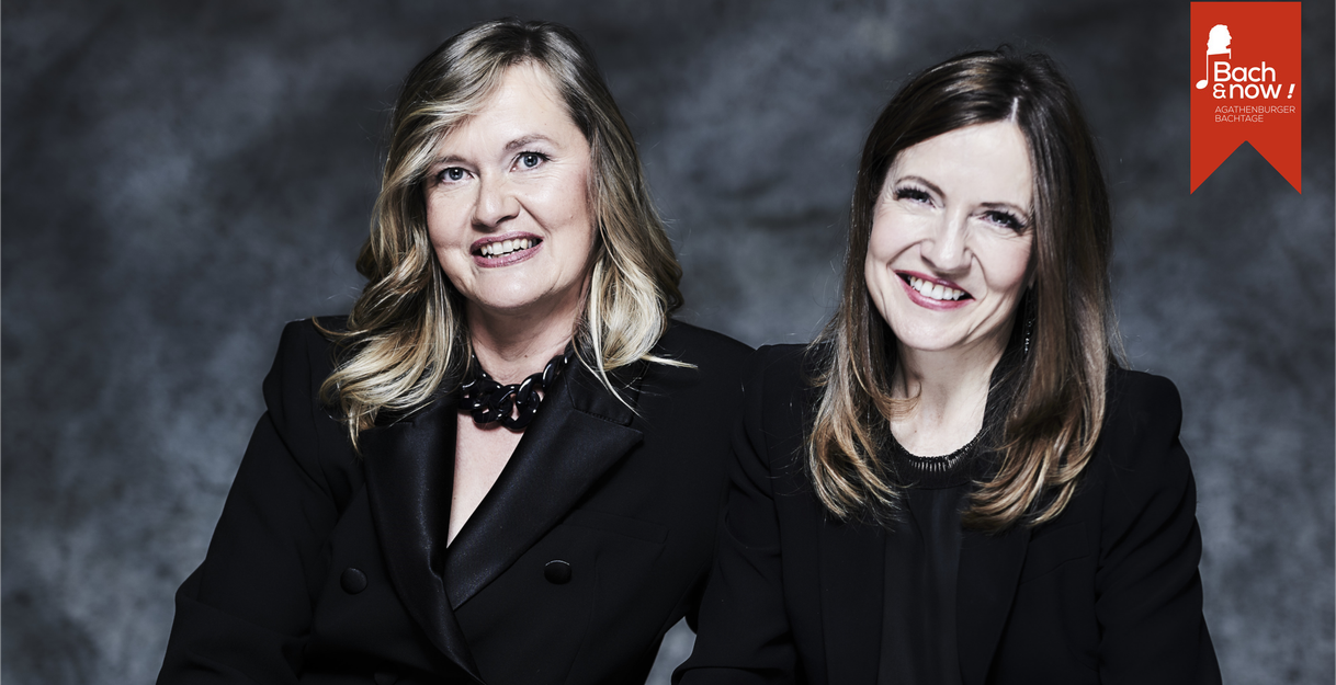 Zwei lächelnde Frauen in schwarzer Kleidung vor grauem Hintergrund mit Bach & Now Logo.