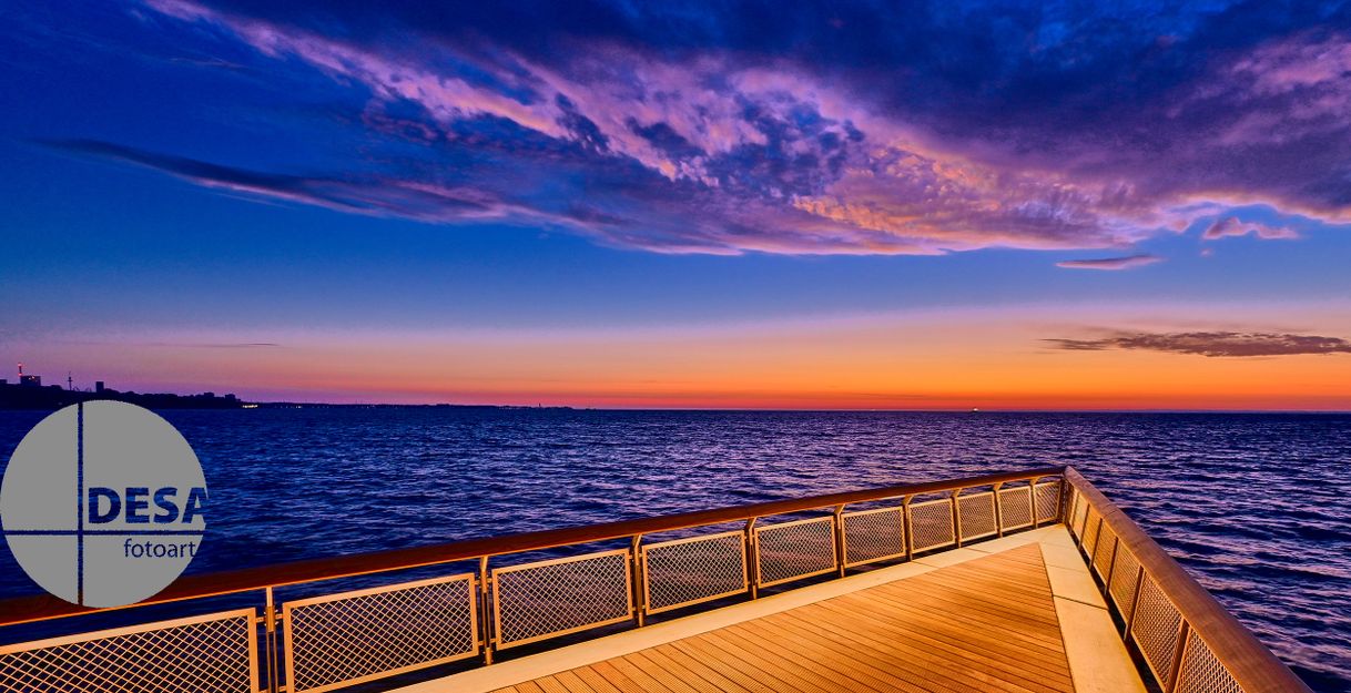 Seebrücke bei Sonnenaufgang mit farbenfrohem Himmel und ruhigem Meer.