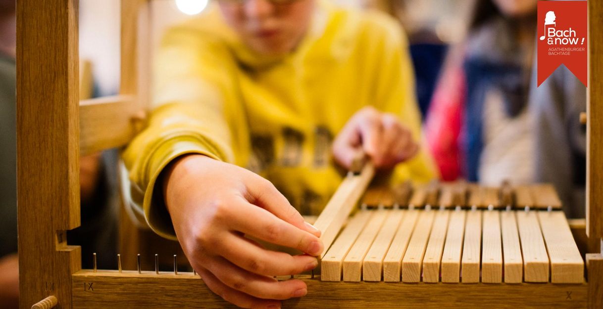 Nahaufnahme einer Person, die an einer hölzernen Orgelkonstruktion arbeitet.