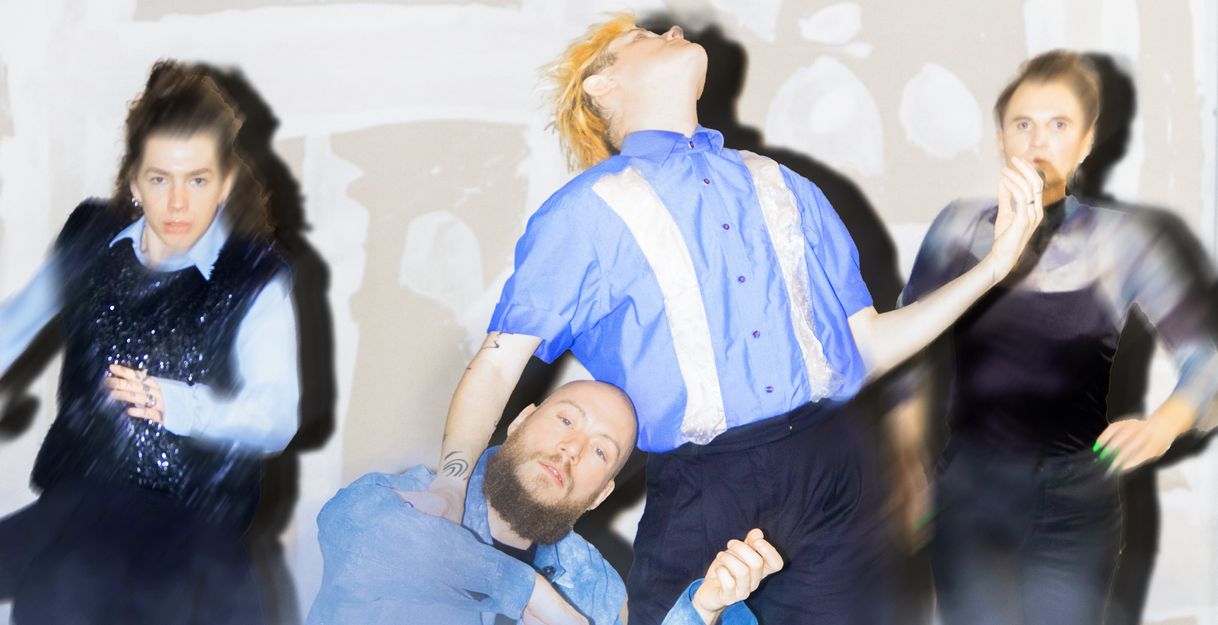 Four performers from the production “Tänze fast vergessener Geister” stand in front of a painted wall and move into different positions.