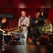 Jazzband spielt auf einer Bühne mit rotem Vorhang.