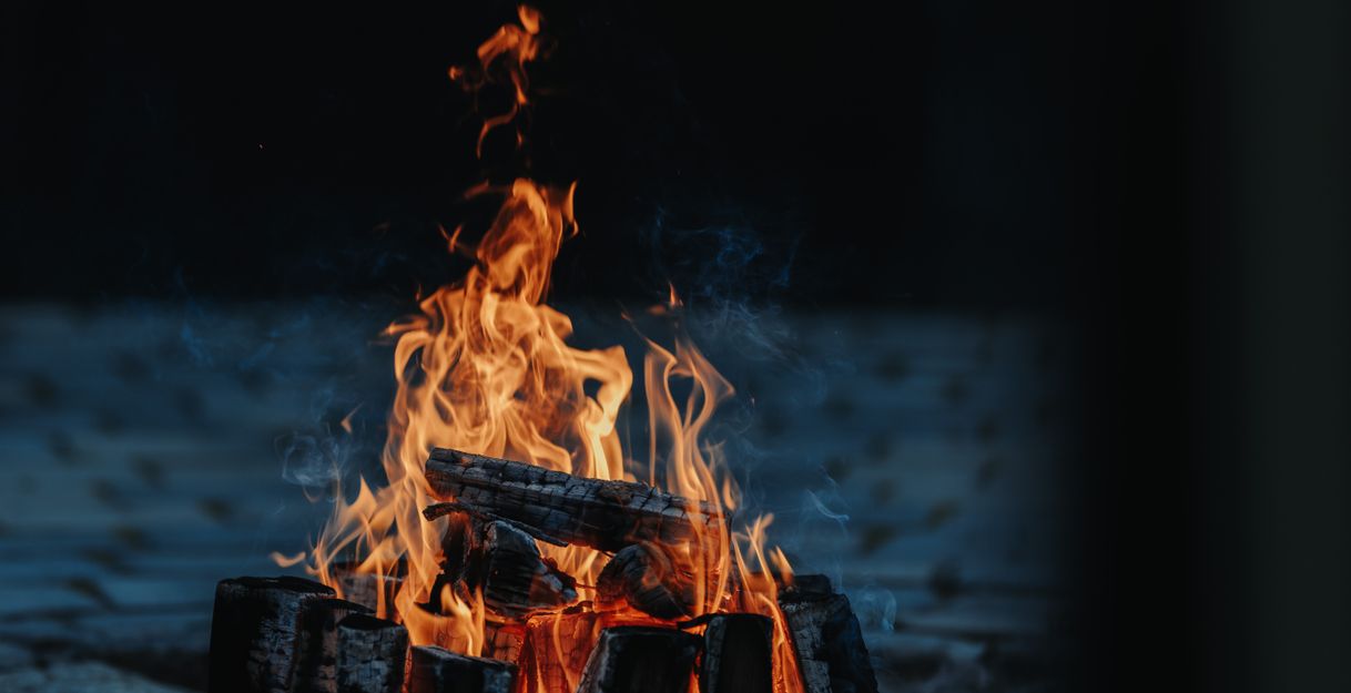 Ein Lagerfeuer mit brennenden Holzscheiten in der Dunkelheit.