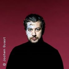 Porträt eines Mannes vor rotem Hintergrund mit künstlerischem Gesichtsmuster.