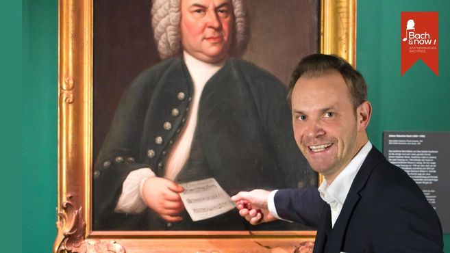 Ein Mann zeigt auf ein Gemälde von Johann Sebastian Bach in einem Museum.