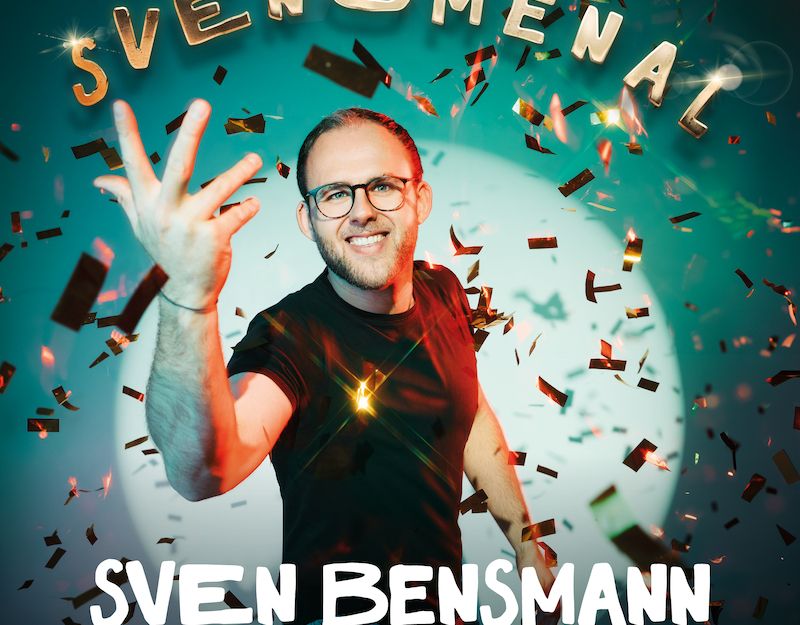 Ein Mann mit Brille und Bart lächelt in die Kamera, umgeben von Konfetti. Oben steht 'SVENOMENAL', unten 'SVEN BENSMANN. COMEDY. MUSIK. LIEBE.'