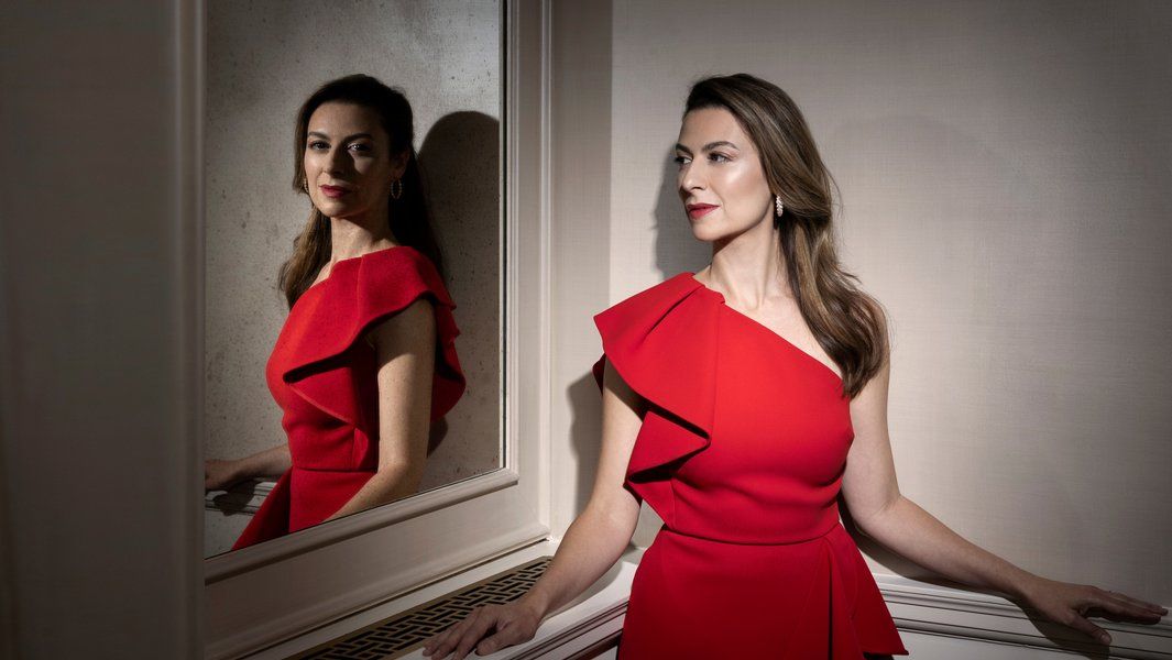 Frau in rotem Kleid vor einem Spiegel.