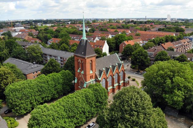 Luftaufnahme einer Kirche in einer Wohngegend mit vielen Bäumen.