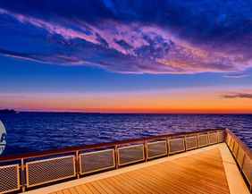 Seebrücke mit Blick auf das Meer bei Sonnenaufgang, der Himmel ist in Blau- und Orangetönen gefärbt.