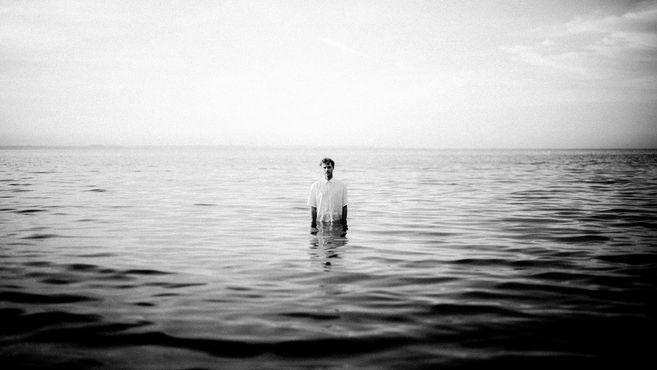 Person steht im Wasser, schwarz-weiß Foto.