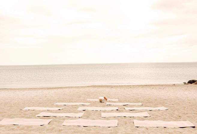 Yoga-Matten auf einem sandigen Strand mit Blick auf das Meer.