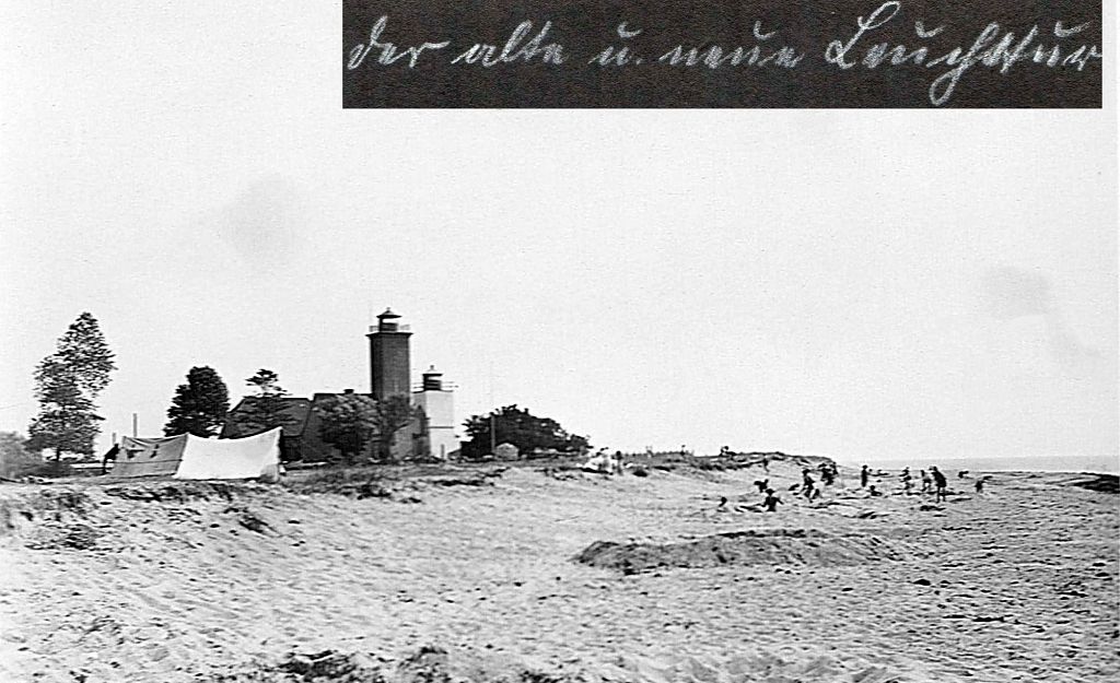 Historisches Foto eines Leuchtturms an einem Strand mit Menschen im Hintergrund.